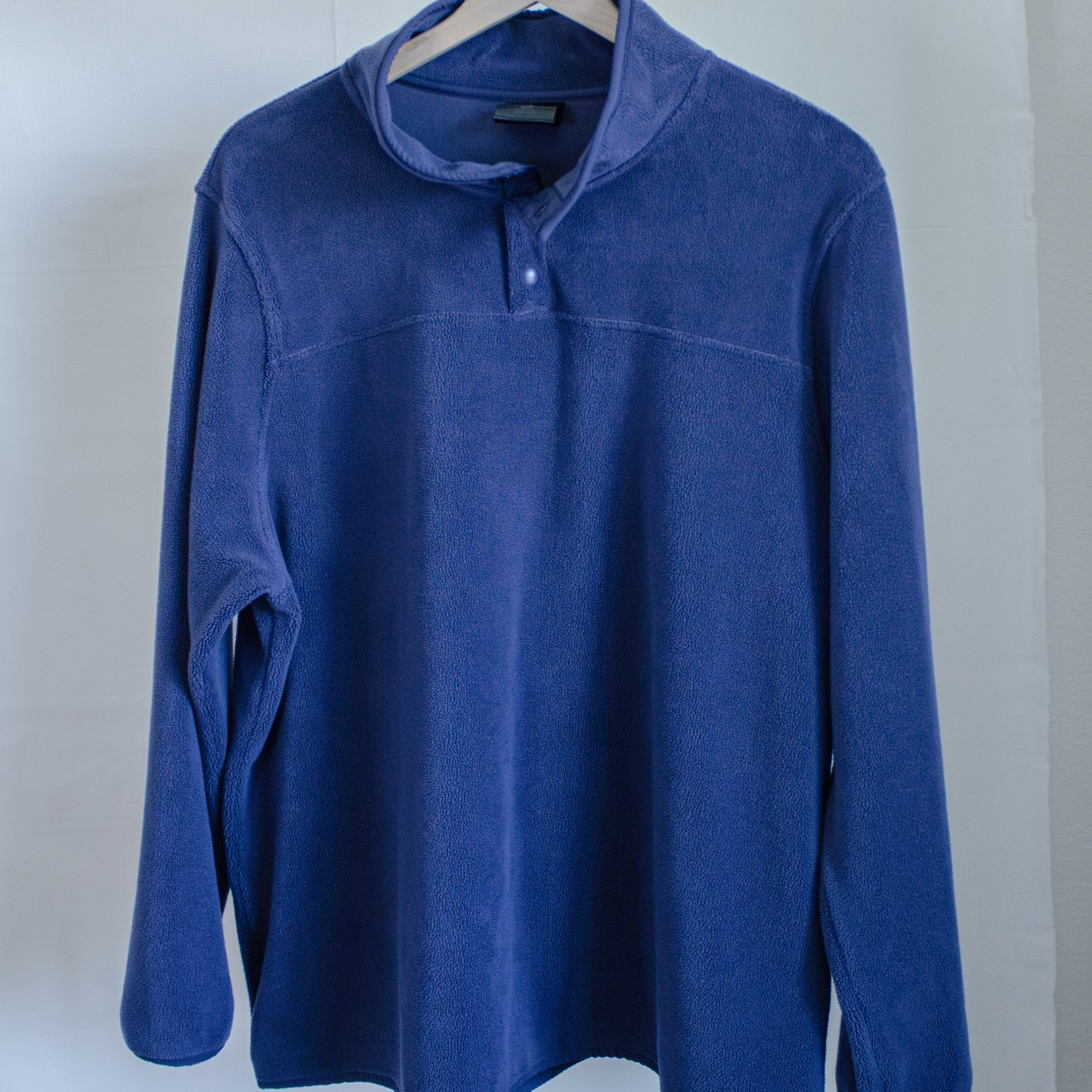 Blue fleece pullover on a hanger against a white background