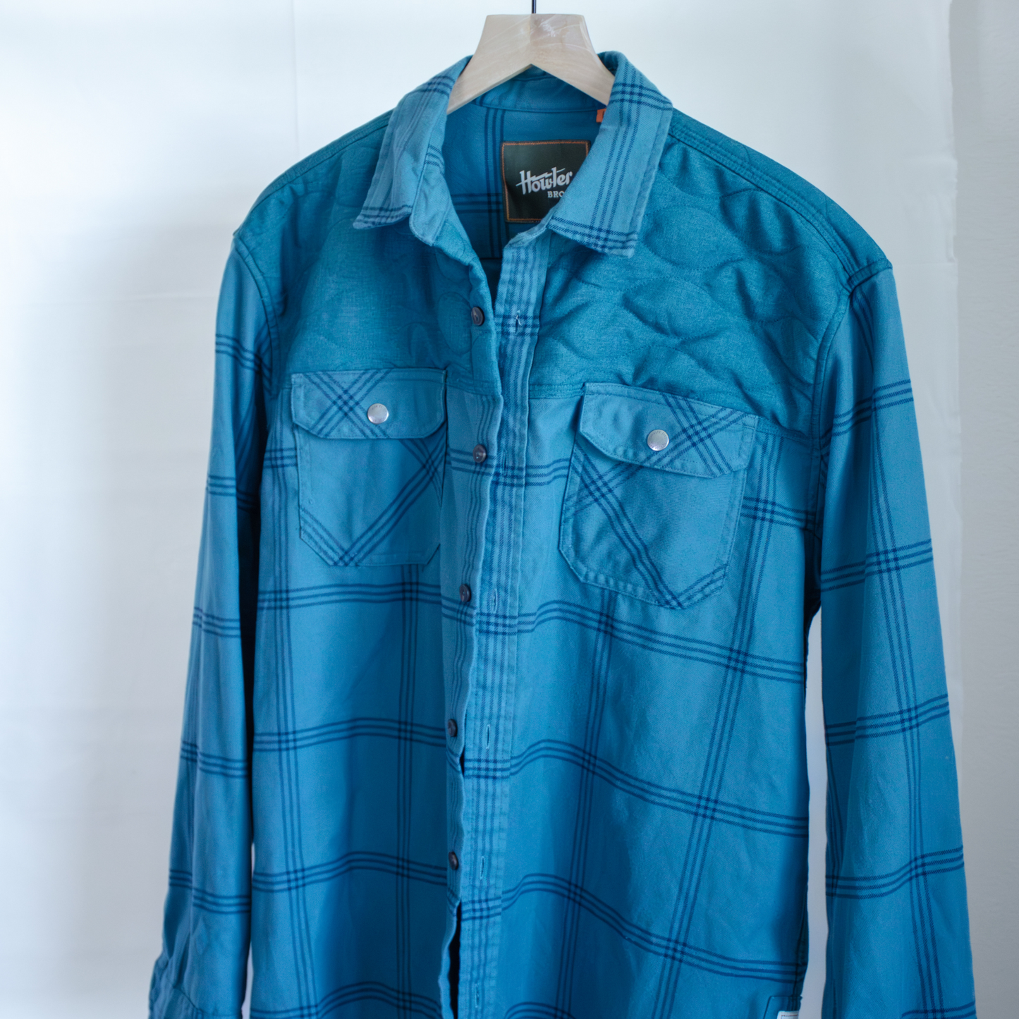 Blue plaid shirt on a hanger against a white background