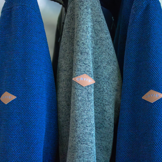 Three jackets, two blue and one green, with an Orvis logo on a plain background.