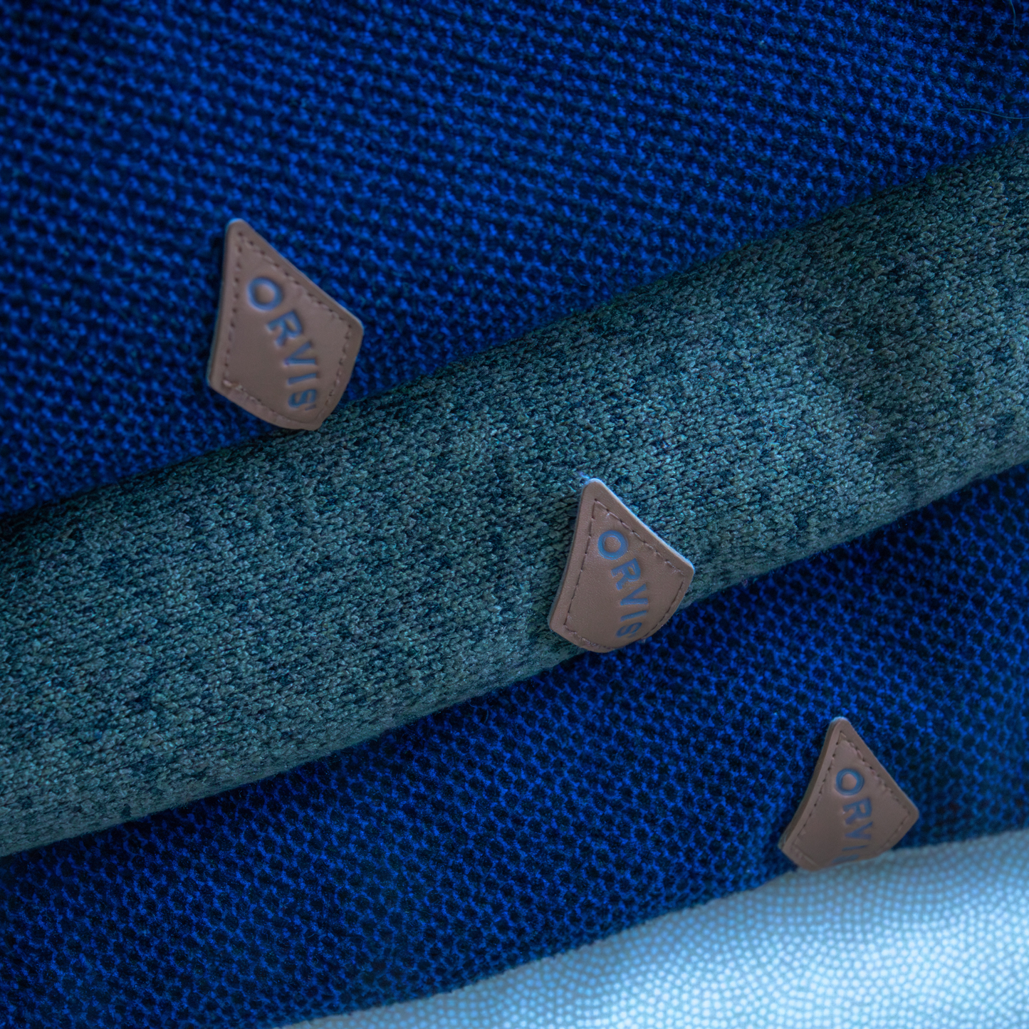 Close-up of Orvis branded sweatshirt sleeves in blue and green.