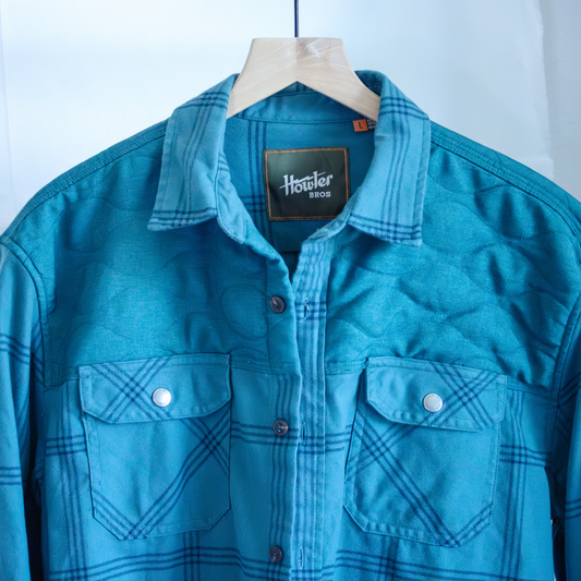 Blue plaid shirt on a hanger with 'Howler Bros' label against a white background